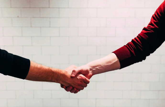 two people shaking hands near white painted wall